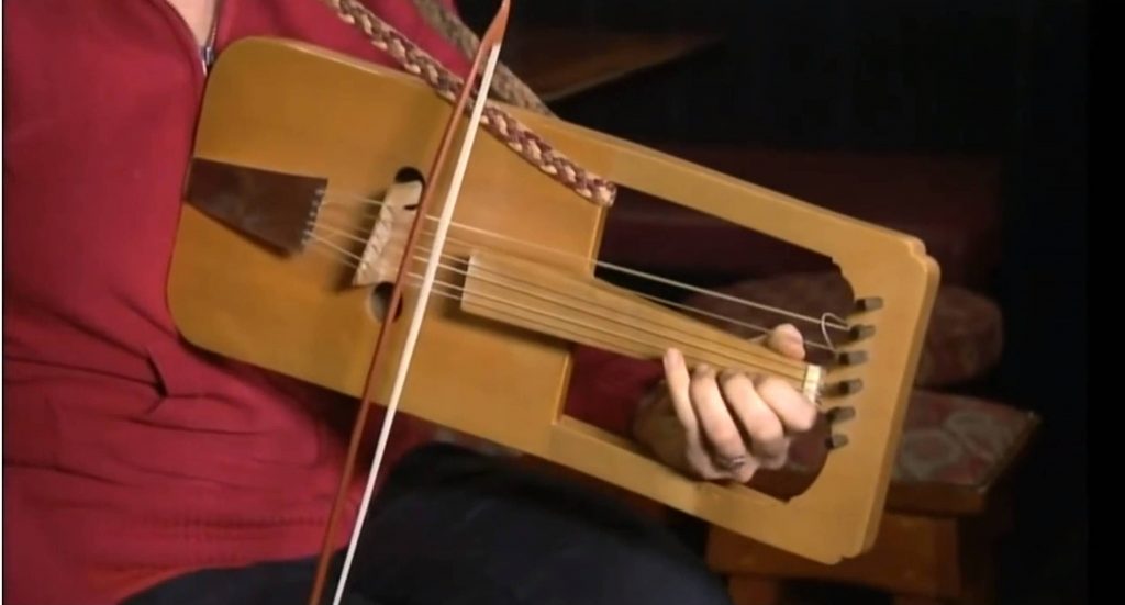 Cass Meurig playing the crwth and demonstrating it to Paul Martin. The solo tune we hear her play is the traditional Welsh Black-Haired Crwth Players Tune. Click on the picture to start the video, which opens in a new window.