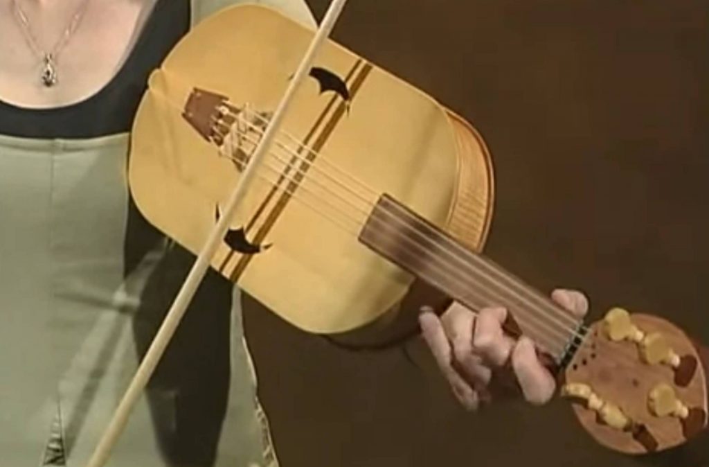 Though the troubadours, trouvères, and jongleurs all sang to their own vielle playing, and minstrels accompanied others’ signing with it, it’s rare to find a modern early music performer who fiddles and sings together. And, though historical fiddles most often had flat bridges, it’s extremely rare to find a modern early music performer playing with one. Dr. Linda Marie Zaerr is dedicated to historically accurate performance of medieval music and literature, and she does both. Click video to play (51 seconds long) – opens in new window.